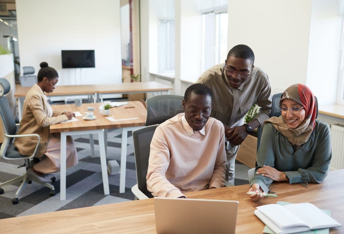 An agency team working across laptops around a shared table